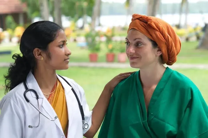 An Ayurvedic doctor talking with a guest in a resort garden in Kerala