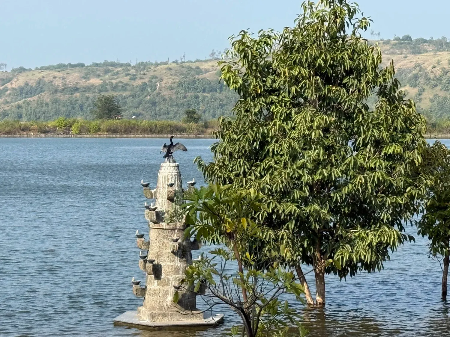 Stone lamp tower in the lake at Toyam Resort with a cormorant drying its wings